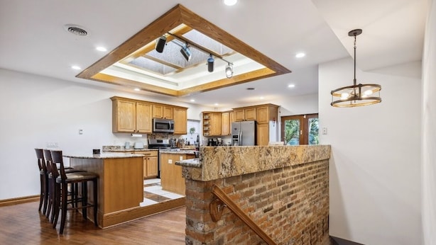 A modern kitchen with a central island, wooden cabinets, and a skylight. - Over 4500 sqft of Luxury living [Billiards table, Arcade room, 5 BR & 4 BA] (Cleveland)