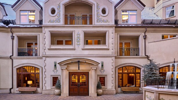 A multi-story building with a central entrance, balconies, and a fountain.