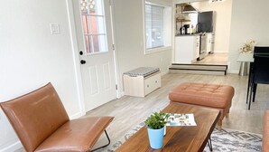 A modern living room with a wooden coffee table, two brown leather chairs, a blue potted plant, and a patterned rug.