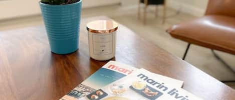A magazine on a wooden table with a potted plant and a candle.