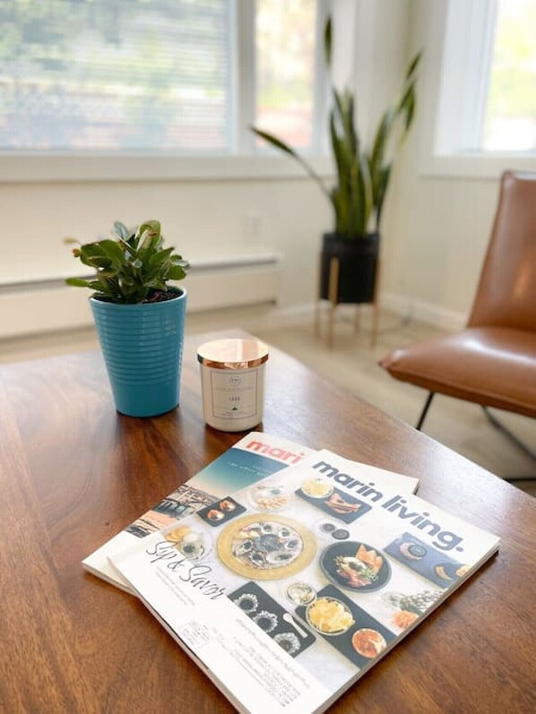 A magazine on a wooden table with a potted plant and a candle. - Hip and chic one bedroom apartment. (San Anselmo)