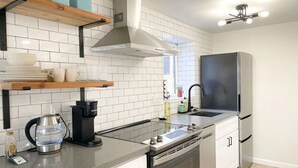 A modern kitchen with white tiled backsplash, stainless steel appliances, and a black countertop.