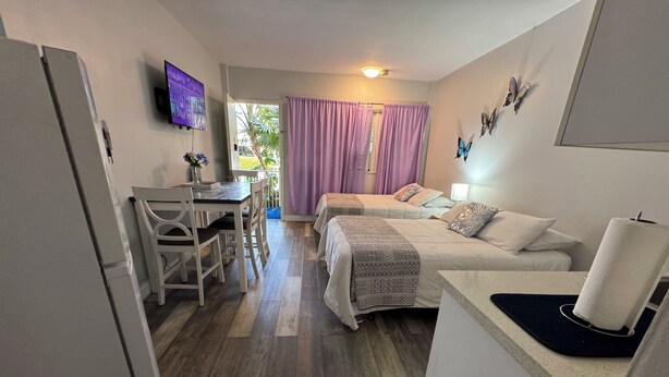 Una habitación con una cama, un escritorio, una silla, un televisor y una ventana con cortinas.
