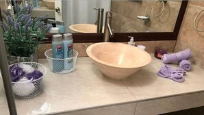 Un baño con un lavabo de madera grande, un espejo, un perchero para toallas y artículos de aseo.