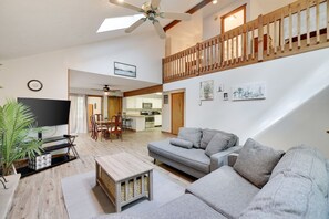 Relax in this spacious living area with a high ceiling, featuring a sofa, coffee table, and mounted TV.