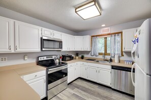 Enjoy cooking in this well-equipped kitchen with an oven, dishwasher, and light-colored countertop.