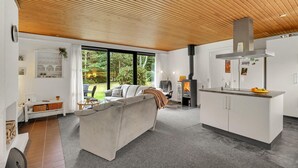 A modern living room with a sofa, a fireplace, and a kitchen area with cabinets and a countertop. - Lovely home in Højslev with WiFi (Højslev)