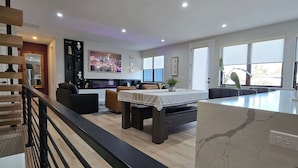 Un salon moderne avec un coin repas, un escalier et une cuisine en arrière-plan.