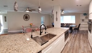 A modern kitchen with granite countertops, a sink, and a dining area with a table and chairs.