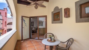 A balcony with a table, chairs, a ceiling fan, and a door leading to an interior space. - Gecko Getaway- a stone's throw from West Bay Beach (Roatan)