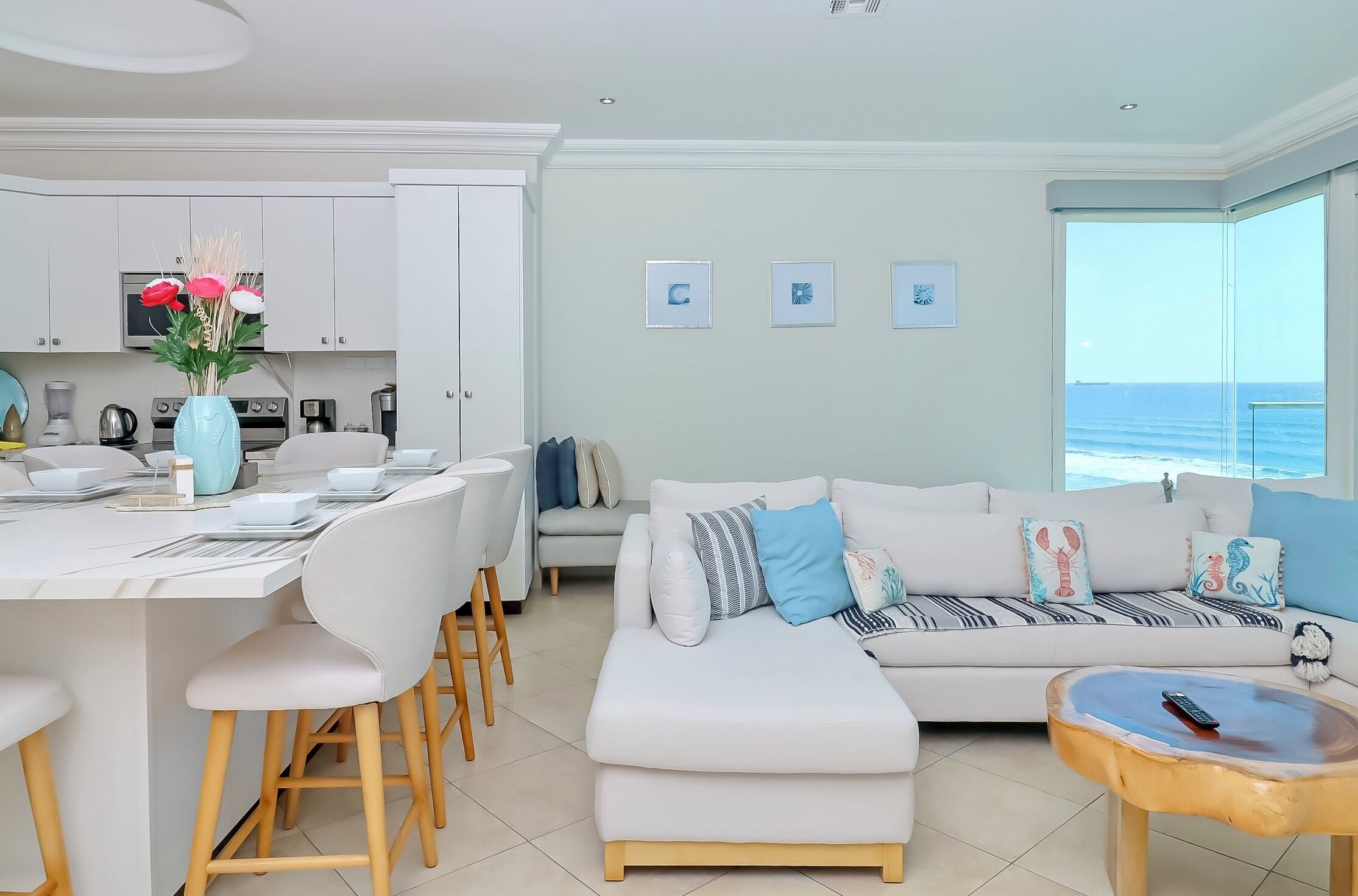 Una sala de estar moderna con un sofá blanco, una mesa de centro y un comedor con sillas y una mesa blanca.