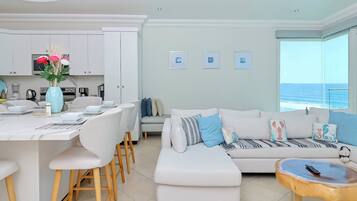Una sala de estar moderna con un sofá blanco, una mesa de centro y un comedor con sillas y una mesa blanca.