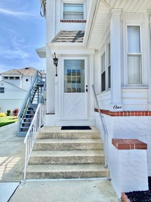 A two-story house with a white exterior, a front door with a glass panel, and a set of concrete steps leading to the entrance. - Everything you need! Steps to Beach-Margate-Restaurants-Stores -Sleeps 4 guests (Ventnor City)