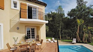 A two-story house with a balcony, a swimming pool, and outdoor furniture.