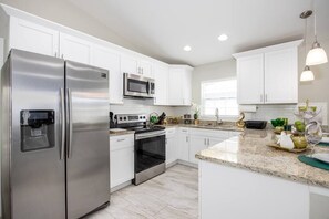 Enjoy cooking in this well-equipped kitchen with a refrigerator, oven, and white cabinetry.