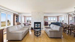 A spacious living room with a fireplace, two sofas, a coffee table, and a dining area with chairs. - Spacious 4 bedrooms Villa, 30 min from Moncton (Cocagne)