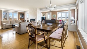 A spacious living room with a large wooden dining table, comfortable seating, and a fireplace. - Spacious 4 bedrooms Villa, 30 min from Moncton (Cocagne)