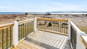 A wooden deck with a railing overlooking a beach. - Spacious 4 bedrooms Villa, 30 min from Moncton (Cocagne)