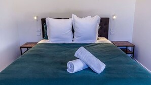 A neatly made bed with a green bedspread, two white pillows, and a rolled white towel on the bed. There are two bedside tables with lamps on either side of the bed. - The Green Room Maryburn Magic (Twizel)