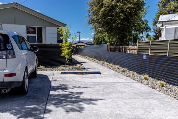 A parking area with a white car, a small tree, and a metal fence. - The Green Room Maryburn Magic (Twizel)