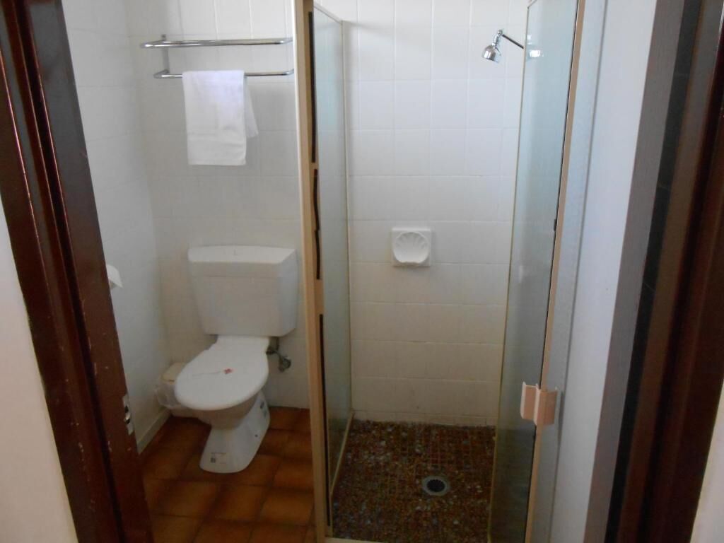 Un baño pequeño con inodoro, ducha y puerta de cristal.