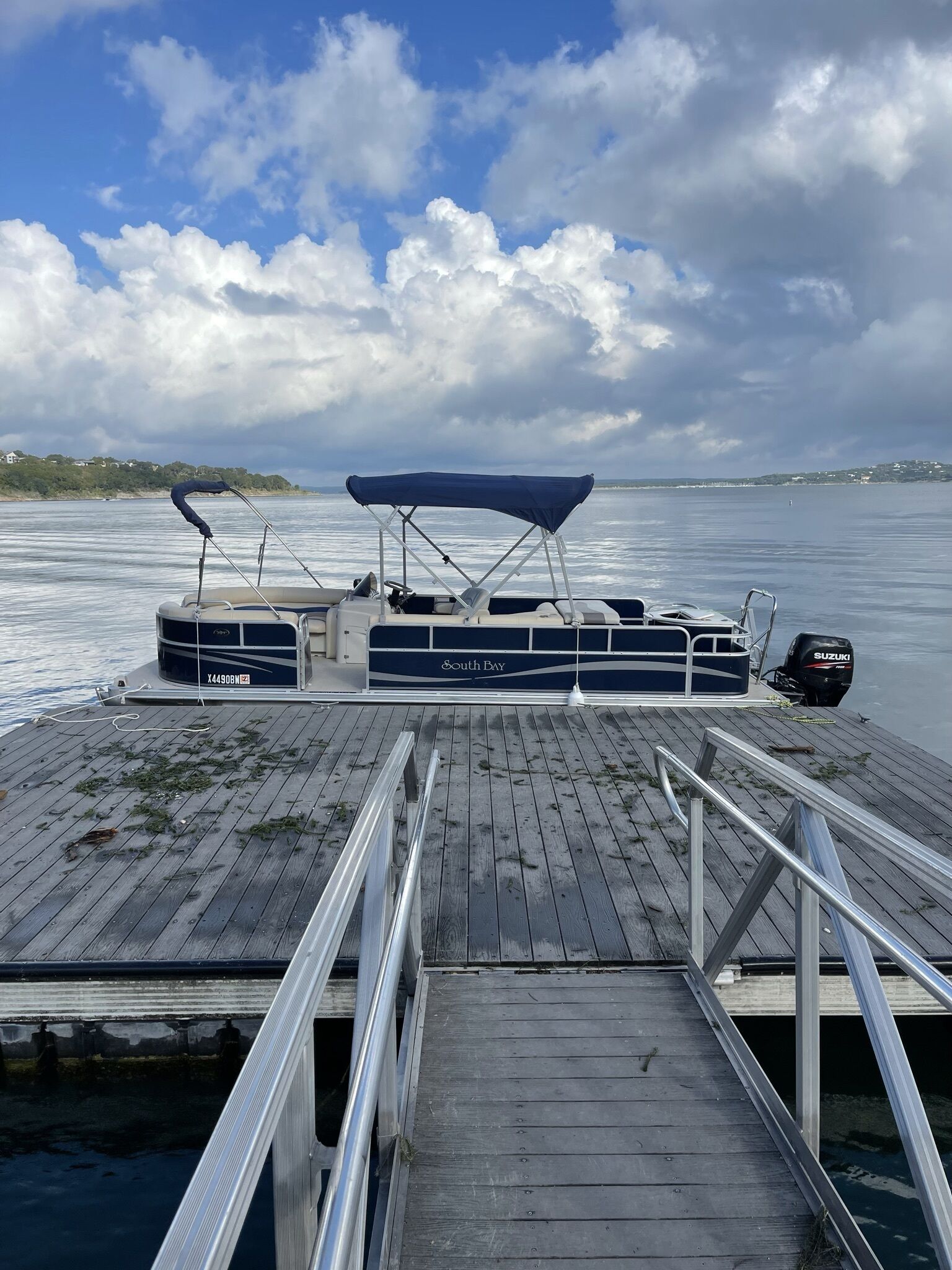 Un bote atracado en un muelle de madera con una cubierta, un motor fueraborda Suzuki y el nombre “South Bay” en el costado.