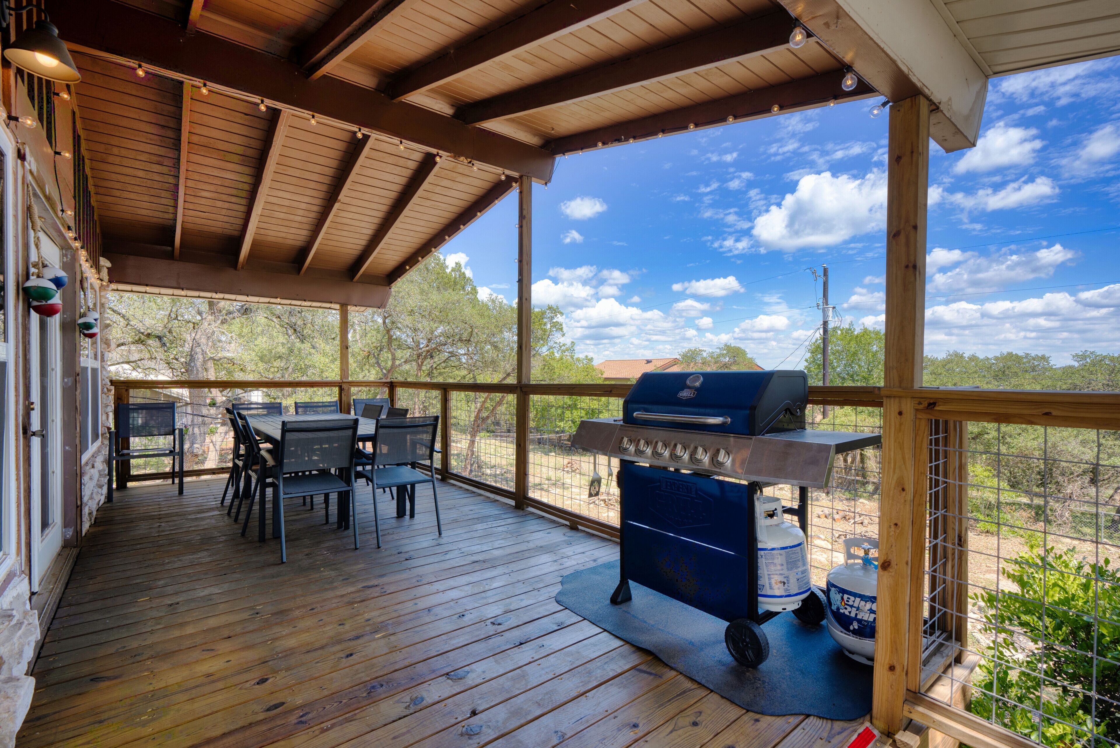 Un espacio al aire libre cubierto con una terraza de madera, una parrilla y una mesa con sillas.