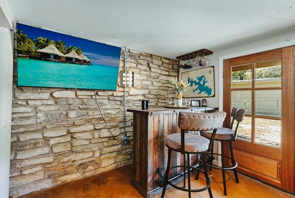 A bar area with stone walls, a wooden counter, and two bar stools.