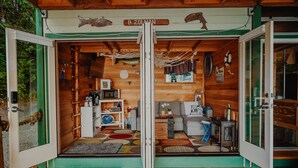 Interior acogedor de una cabaña con fachada de madera, una puerta verde y una señal con el nombre visible.