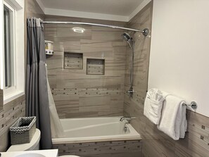 Een bad/douchecombinatie, een haardroger, handdoeken, zeep