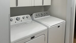 A laundry area with two Maytag washers and dryers, white cabinets above, and a wooden floor. - Wendover's most comfortable house for rent. (West Wendover)