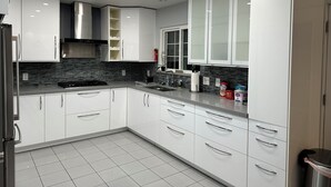 A modern kitchen with white cabinets, a black tiled backsplash, and stainless steel appliances. - Wendover's most comfortable house for rent. (West Wendover)
