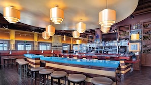 A bar area with a long counter, multiple stools, and hanging pendant lights. - Club Wyndham Resort 3 Bedroom Presidential Ocean View (Oceanside)