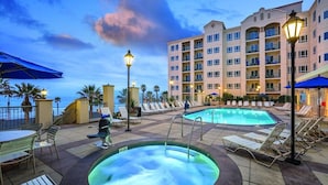 A hotel pool area with two hot tubs, lounge chairs, and a building in the background. - Club Wyndham Resort 3 Bedroom Presidential Ocean View (Oceanside)