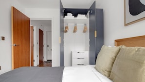 A bedroom with a bed, a wardrobe, and a door leading to another room. - Hip Islington 2BR w/ Day Porter & Balcony, nr Kings Cross, by Blueground (London)