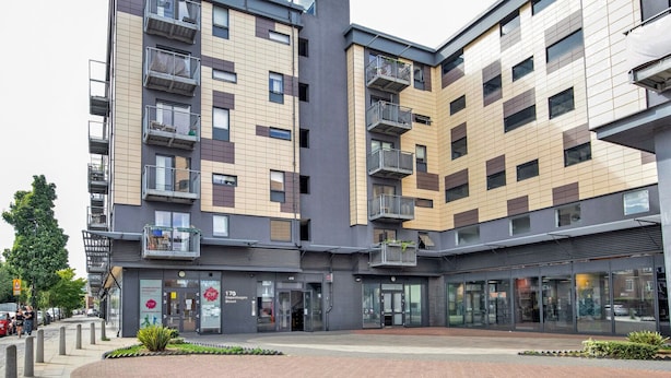 A modern multi-story building with balconies, a ground-level entrance, and a visible storefront. - Hip Islington 2BR w/ Day Porter & Balcony, nr Kings Cross, by Blueground (London)