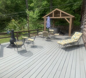 Une terrasse en bois avec des meubles d’extérieur, un barbecue et un espace salon abrité.