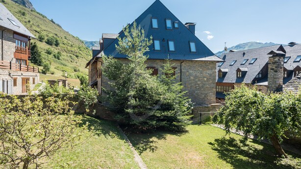 A stone building with a steeply pitched roof, surrounded by lush greenery and a clear sky. - Aiguamoig by SeaMount Rentals (Gessa)
