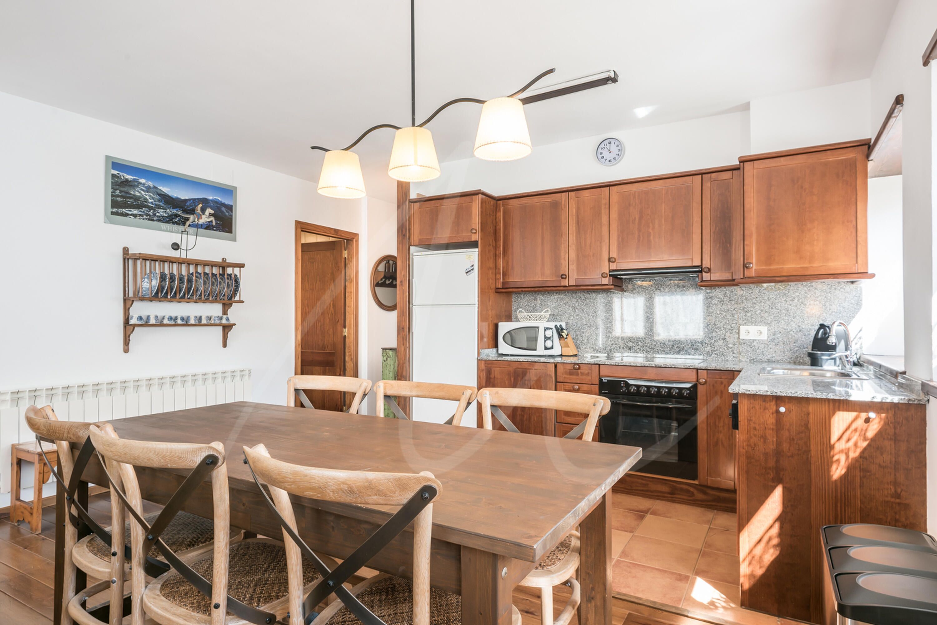A modern kitchen with wooden cabinets, a granite countertop, and a dining area with a wooden table and chairs.