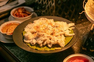 A plate of food with a yellow leaf underneath, accompanied by bowls of side dishes.