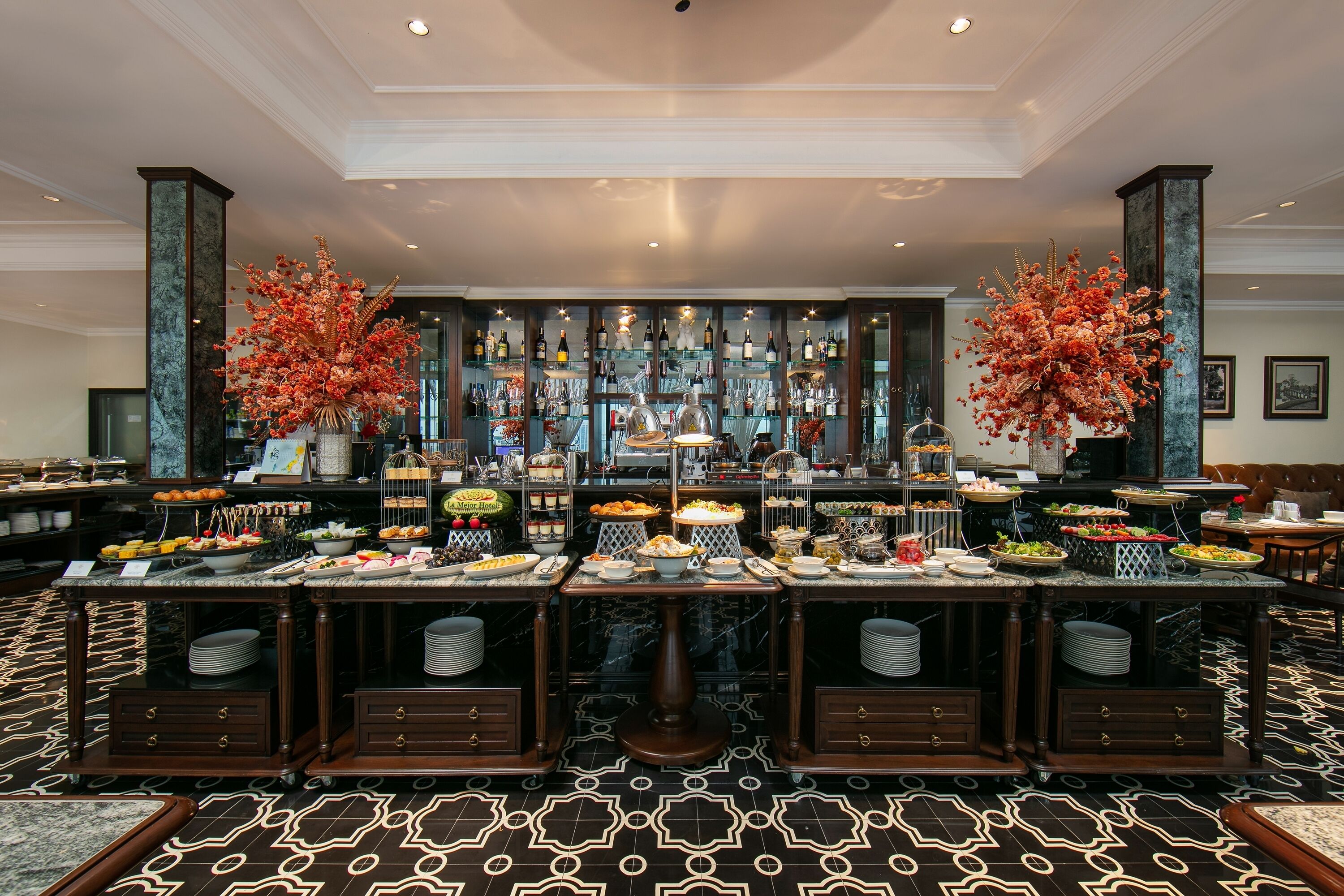A buffet setup with various food items and a bar area in the background.