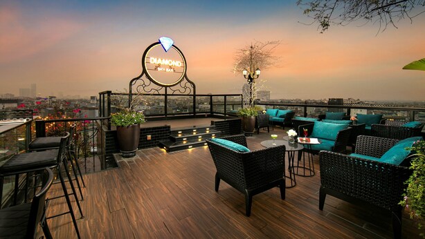 A rooftop bar with a sign reading "Diamond Sky Bar," featuring outdoor seating with wicker furniture and potted plants.