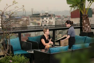 A balcony with wicker furniture, a palm tree, and a city view.