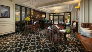Een hotel lobby met een vloer met patroon, zitgedeeltes, een receptiebalie en een kroonluchter.