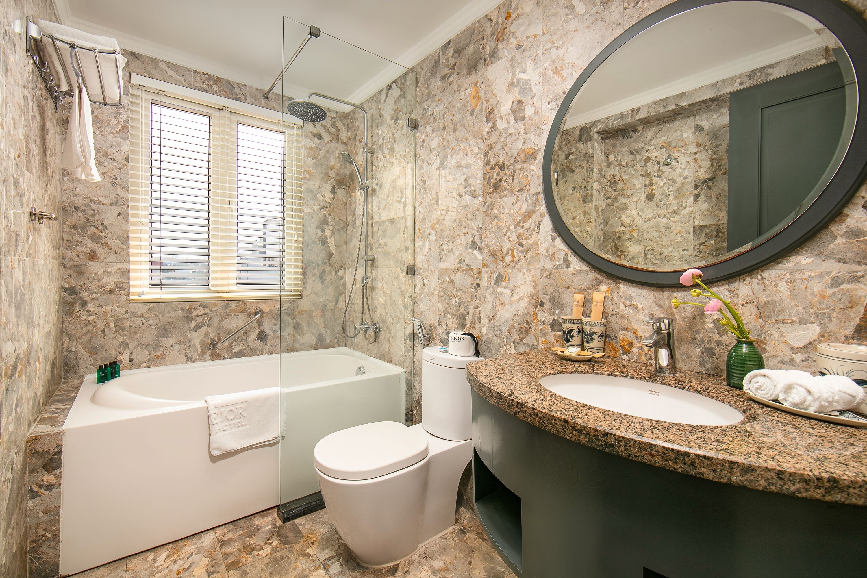 A bathroom with a bathtub, toilet, sink, and a large mirror.