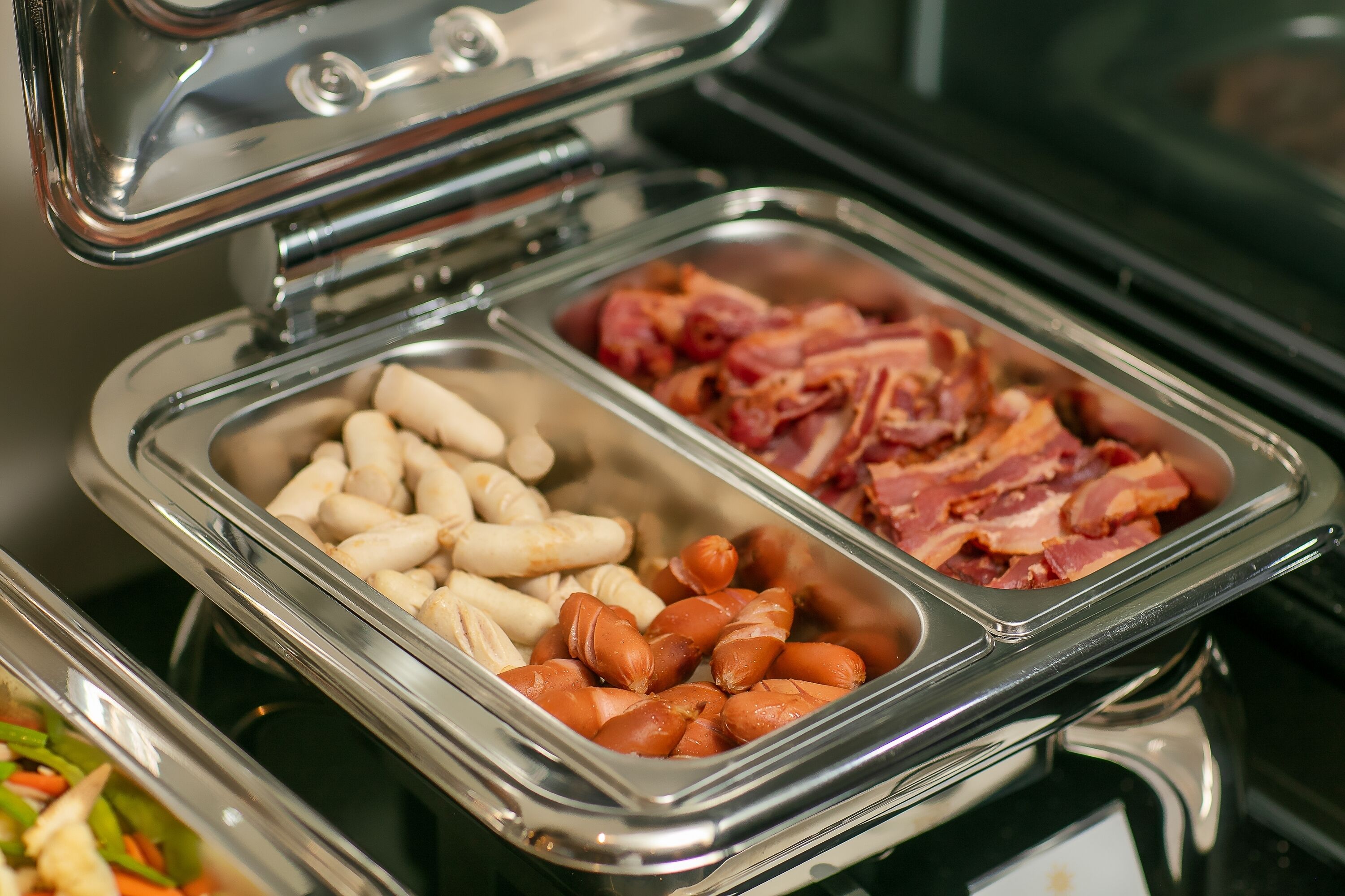 A buffet with various food items including sausages and bacon.