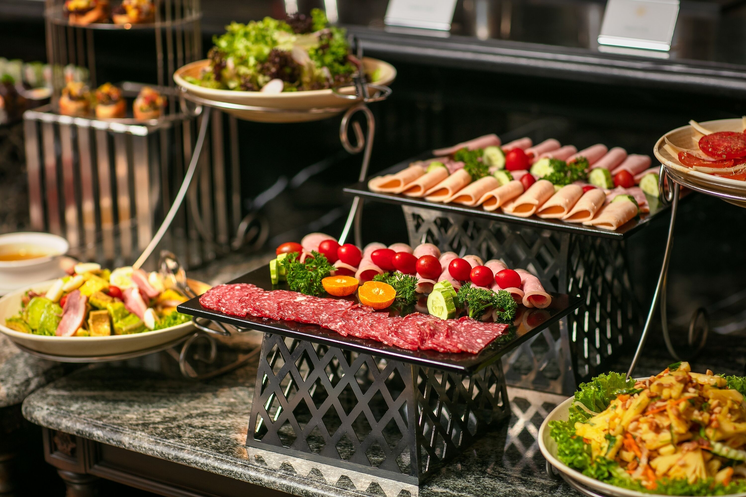 Ein reichhaltiges Buffet mit verschiedenen Speisen, darunter Fleisch, Käse und Salate.