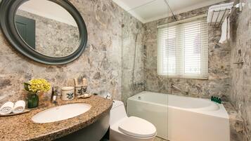 Een badkamer met een wastafel met granieten blad, een toilet en een bad.