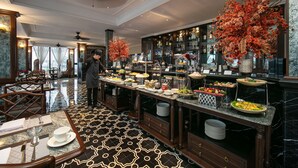 A hotel dining area with a buffet setup, marble flooring, and a person in the background.