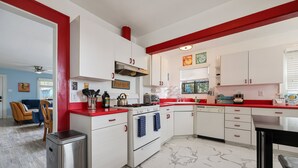 A kitchen with white cabinets, red countertops, and a stainless steel refrigerator. - 2 br, 2 bth, fully fenced home - The Sunnyside Up Beach Cottage (Oceanside)